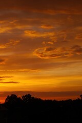 The sky is orange and the clouds are white. Phone wallpaper. Vertical background.
