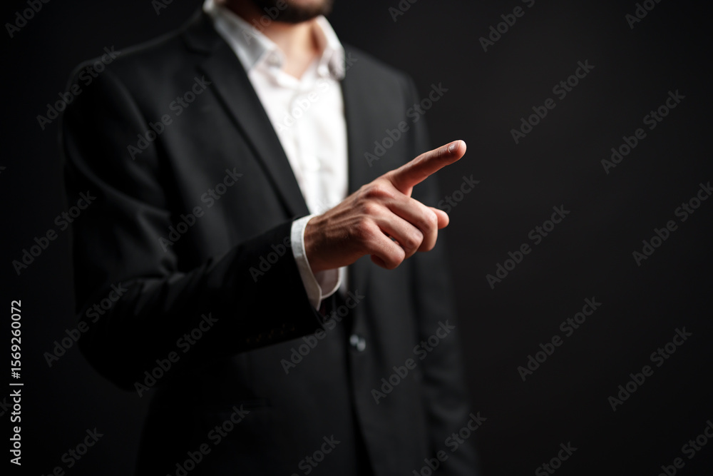 Poster man in suit gestures with finger pointing while standing against dark background expressing authorit