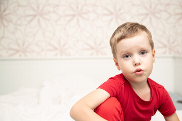 Sad little boy sitting in red t-shirt and almost crying, breathing nebulizer