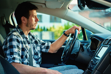 Man driving car and looking ahead with focus, sitting in modern vehicle interior. Concept of daily...