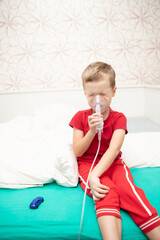 Sad little boy sitting in red t-shirt and almost crying, breathing nebulizer