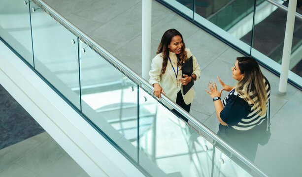 Female colleagues having a corporate discussion in office atrium