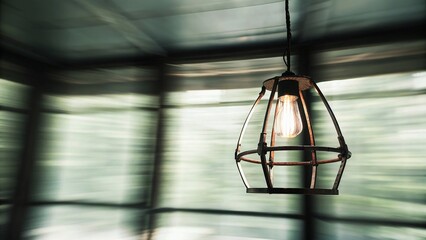 Rustic Metal Pendant Light with Glowing Bulb and Soft Bokeh in Background
