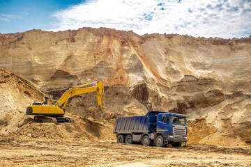 The process of loading sand in a sand quarry. Trucks are waiting for cargo.