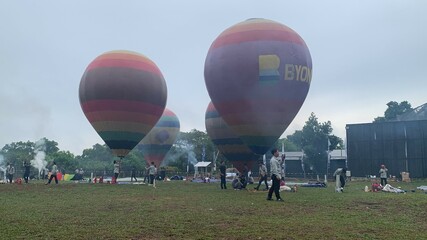 Colorful hot air balloons festival display distinct horizontal stripes are being inflated on the cloudy sky provide  backdrop. 