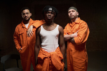 Three young adult men standing together in prison group therapy session, including Black man in...