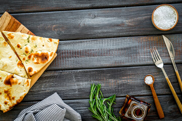 Italian focaccia with cheese and rosemary on dark wooden background top-down copy space