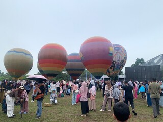 Colorful hot air balloons festival display distinct horizontal stripes are being inflated on the cloudy sky provide  backdrop. 