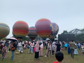 Colorful hot air balloons festival display distinct horizontal stripes are being inflated on the cloudy sky provide  backdrop. 