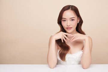 Naklejka premium A beautiful young Asian woman with clean, fresh skin against a beige background. Skincare, facial treatment, cosmetology, beauty, and spa. An elegant portrait of an Asian woman.
