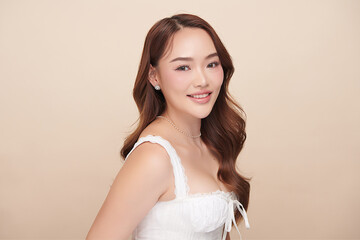 A beautiful young Asian woman with clean, fresh skin against a beige background. Skincare, facial...