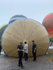 Colorful hot air balloons festival display distinct horizontal stripes are being inflated on the cloudy sky provide  backdrop. 