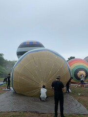 Colorful hot air balloons festival display distinct horizontal stripes are being inflated on the cloudy sky provide  backdrop. 
