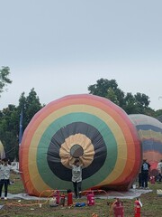 Colorful hot air balloons festival display distinct horizontal stripes are being inflated on the cloudy sky provide  backdrop. 