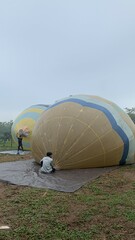 Colorful hot air balloons festival display distinct horizontal stripes are being inflated on the cloudy sky provide  backdrop. 