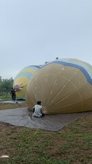 Colorful hot air balloons festival display distinct horizontal stripes are being inflated on the cloudy sky provide  backdrop. 