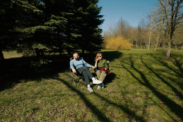 Couple enjoys a sunny day together in outdoor folding chairs amidst nature's beauty