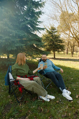 Couple enjoying a relaxing afternoon in outdoor folding chairs amidst trees and nature