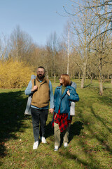 A couple strolls through a green park on a sunny day