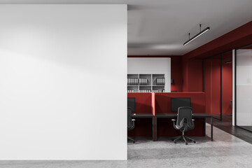 Empty white wall mockup next to modern red office cubicles in a stylish workspace interior with...
