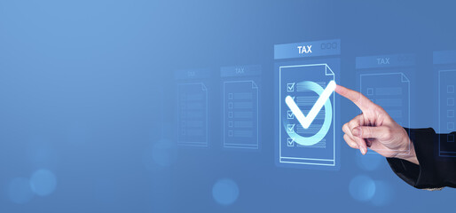 Hand pointing at digital tax document with check mark on transparent screen representing financial...