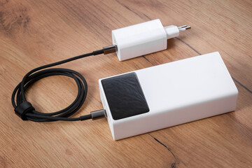 White power bank and charger on a wooden surface.