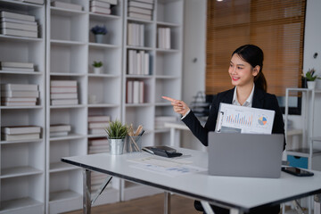 Businesswoman holding financial report document explaining charts and graphs via video conference using laptop computer working online in office