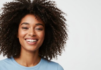 Joyful black woman with voluminous curly hair smiling against a white background