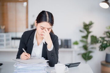 Young asian businesswoman is having headache and tired from working on laptop at the office,...