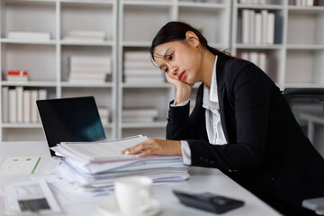 Fototapeta premium Stressed or sad and tired young business asian woman working with laptop at workplace.