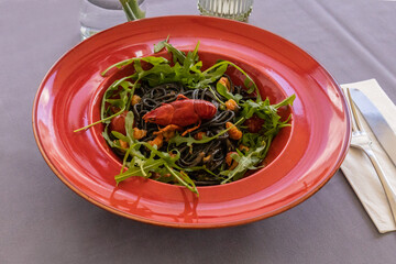 Bright black spaghetti with seafood and succulent crab on fresh rocket, highlighting culinary skill...