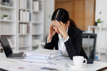 Stressed or sad and tired young business asian woman working with laptop at workplace.