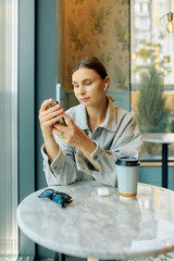 Young woman drinking coffee in cafe and chatting on phone
