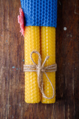 Two yellow textured natural bee wax candles tied with jute rope on rustic wooden table background....
