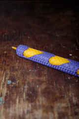 Violet yellow textured natural bee wax candle on rustic wooden table background. closeup shot, copy...