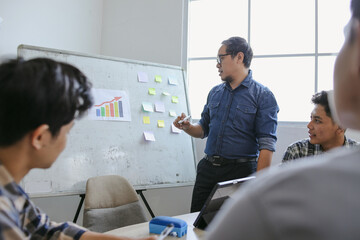 Asian Male Teacher Wearing Glasses Leading Students In Discussion With Papers And Whiteboard Present