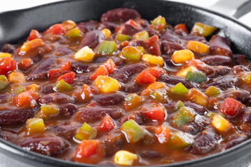 Mexican chilli beans with vegetables in iron pan isolated on white background. Close up