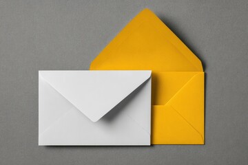 Two envelopes, white and bright yellow, on gray background