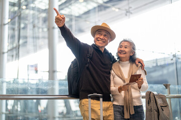 Senior asian couple with luggage checking passport planning trip showing travel preparation at...