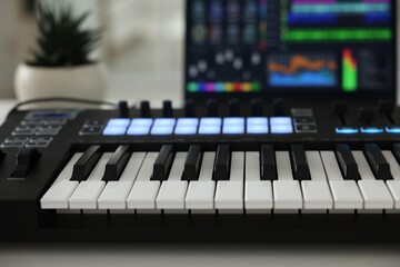 MIDI keyboard and laptop on table indoors, closeup