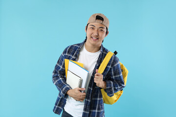 Student with backpack and notebooks on light blue background