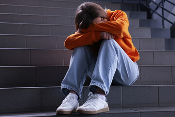 Bullying. Upset teenage girl on stairs indoors