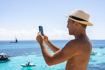 Man taking smartphone photo of boats in Favignana, Sicily
