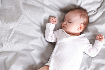 Cute newborn baby sleeping on bed, top view. Space for text
