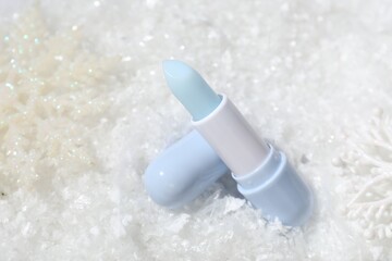 Moisturizing lip balm and Christmas decor on artificial snow, closeup. Winter care