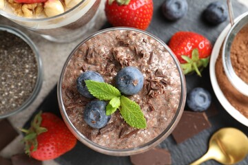 Delicious chocolate pudding with chia seeds, strawberries and blueberries in glass on light grey...