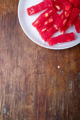 Turkish delight, red locum sticks with hazelnut on white plate, wooden background. Eastern sweets,...