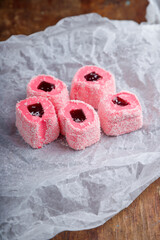 Turkish delight, pink and white locum roll with walnut and jelly on paper, wooden background. Eastern sweets, oriental food. Traditional tasty dessert