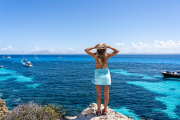 Woman on cliff looking at turquoise sea in Favignana, Sicily