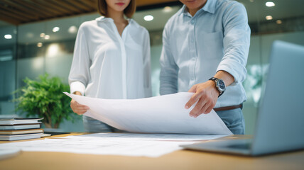 二人のアジア人が書類を確認するオフィス場面